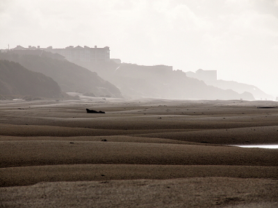 [The wide expanse of sand leads to hillsides shrouded in mist. The sand is not flat ground but little rolling slopes.]